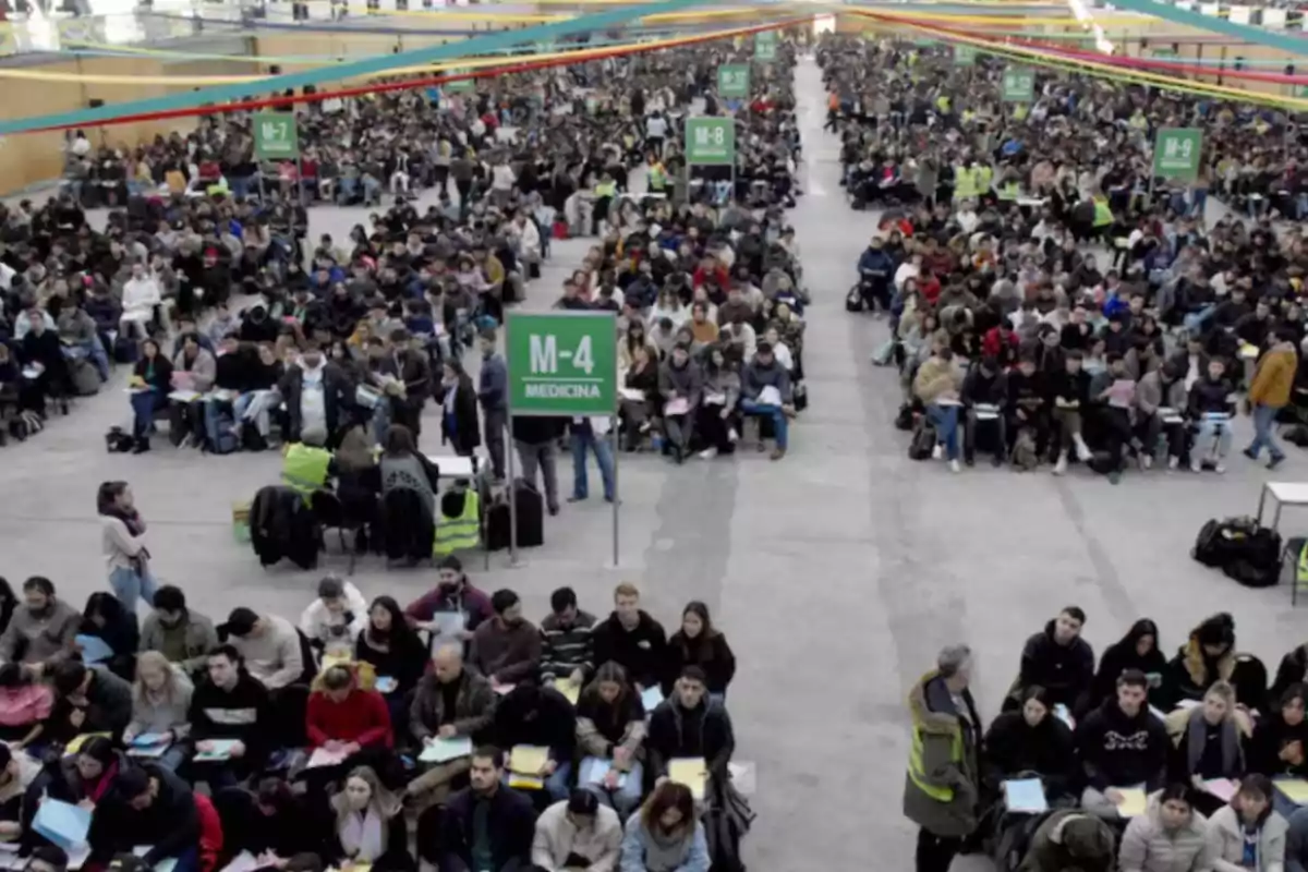 Thousands of people seated in rows inside a large indoor venue while taking a massive medical school entrance exam.