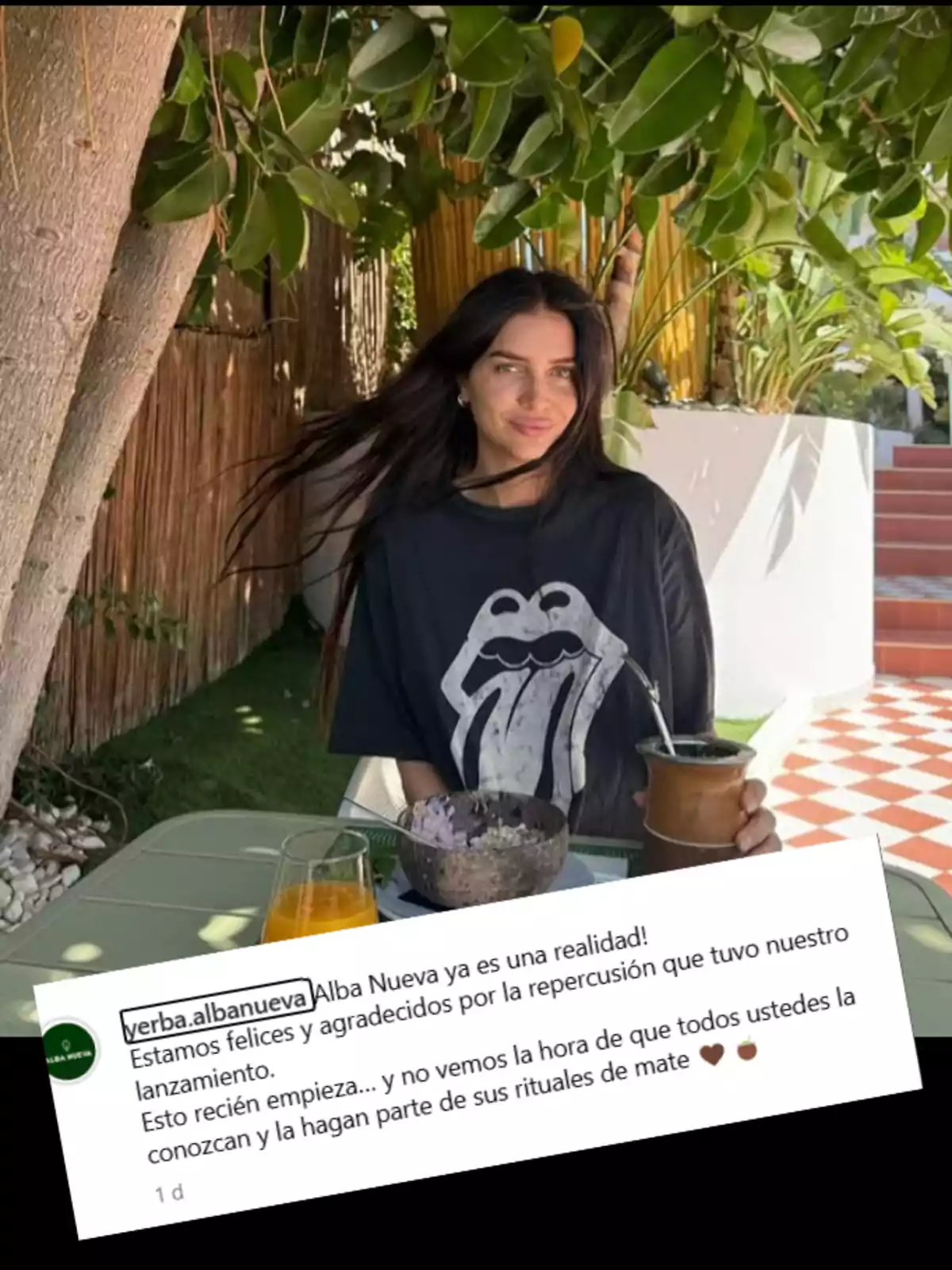 Mujer de cabello largo y oscuro sentada al aire libre bajo un árbol, con una camiseta negra de los Rolling Stones, sosteniendo un mate y con un desayuno y jugo de naranja sobre la mesa, acompañada de un recuadro con un mensaje de agradecimiento por el lanzamiento de un producto llamado Alba Nueva Mujer de cabello largo y oscuro sentada al aire libre bajo un árbol, con una camiseta negra de los Rolling Stones, sosteniendo un mate y con un desayuno y jugo de naranja sobre la mesa, acompañada de un recuadro con un mensaje de agradecimiento por el lanzamiento de un producto llamado Alba Nueva