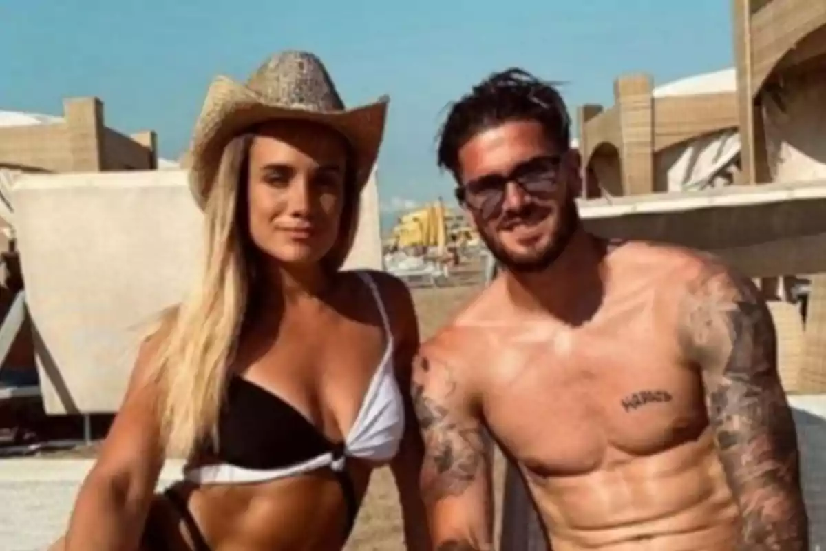 Pareja joven posando en la playa, ella lleva sombrero y bikini, él está sin camiseta y usa gafas de sol Pareja joven posando en la playa, ella lleva sombrero y bikini, él está sin camiseta y usa gafas de sol