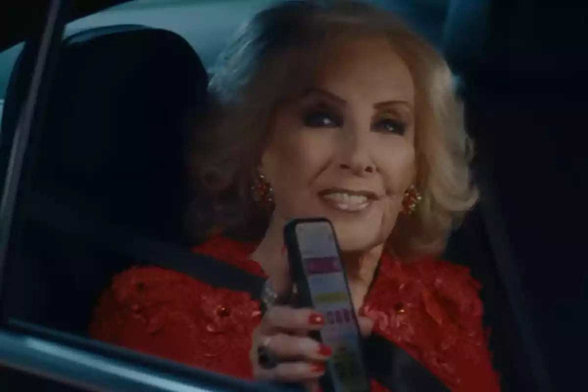 Older woman with blonde hair and a red dress smiles while holding a mobile phone sitting in the back seat of a car Older woman with blonde hair and a red dress smiles while holding a mobile phone sitting in the back seat of a car