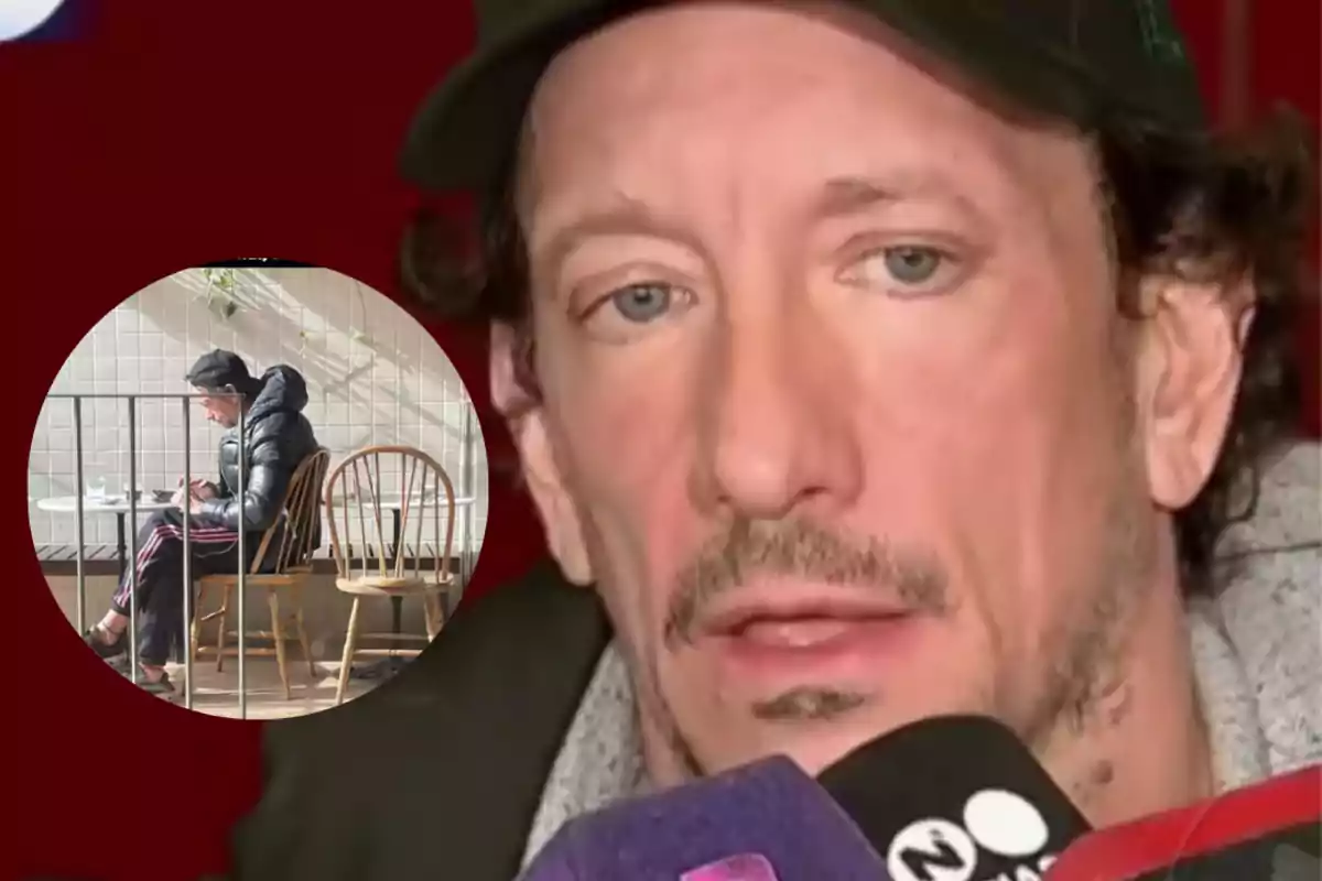 A man wearing a cap and a black jacket gives an interview in front of several microphones while, in a box, he appears sitting alone in a café.