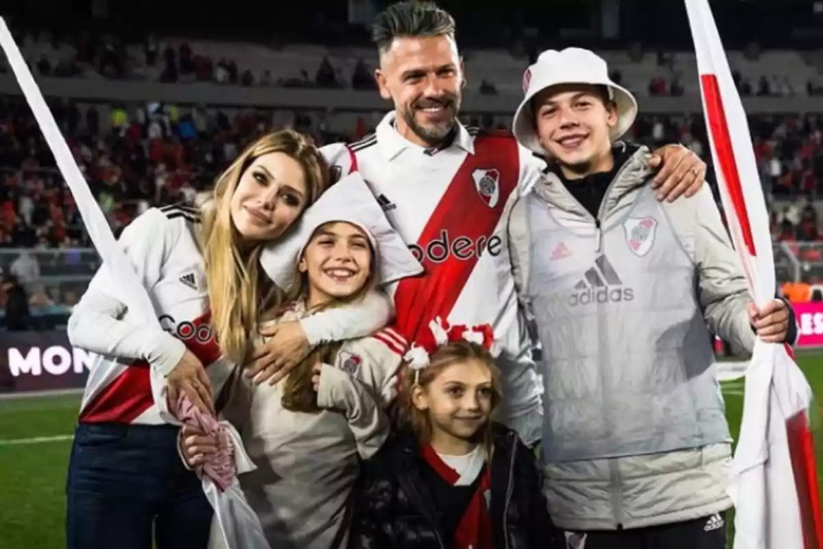 Familia sonriente vestida con camisetas de River Plate posando en un estadio de fútbol Familia sonriente vestida con camisetas de River Plate posando en un estadio de fútbol