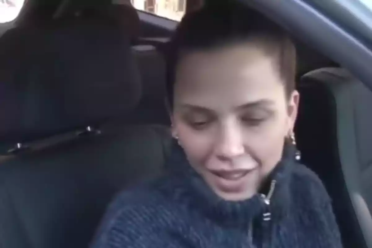 Young woman sitting in the driver's seat of a car looking down and slightly smiling Young woman sitting in the driver's seat of a car looking down and slightly smiling