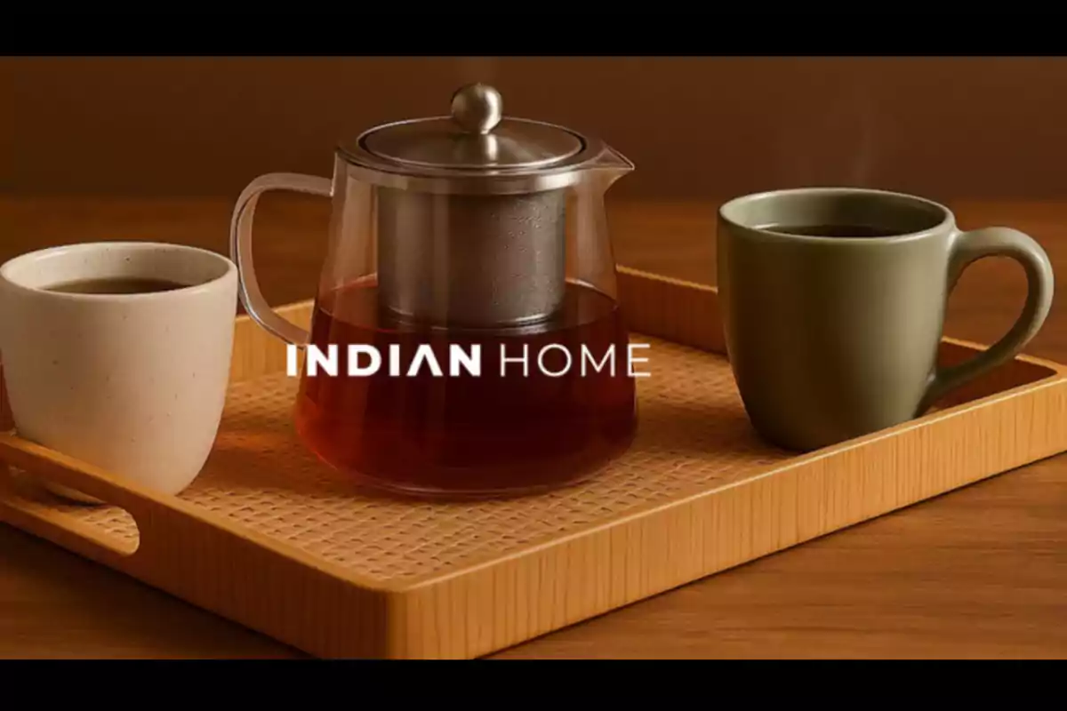 Wooden tray with a glass teapot and two ceramic cups next to the text INDIAN HOME Wooden tray with a glass teapot and two ceramic cups next to the text INDIAN HOME