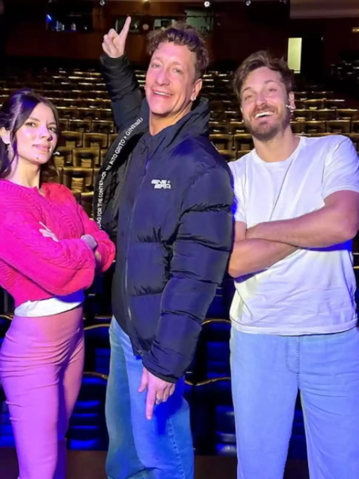 Three people pose smiling in an empty theater with seats in the background. Three people pose smiling in an empty theater with seats in the background.