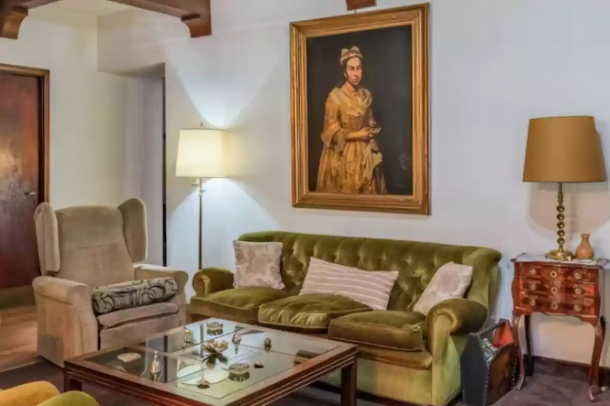 Sala de estilo vintage con sofá verde, sillón beige, mesa de centro de vidrio, lámparas y un cuadro antiguo de una mujer en la pared. Sala de estilo vintage con sofá verde, sillón beige, mesa de centro de vidrio, lámparas y un cuadro antiguo de una mujer en la pared.