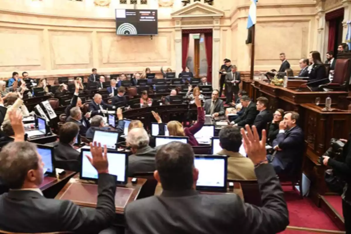 Sesión parlamentaria con legisladores votando y levantando la mano en un recinto oficial Sesión parlamentaria con legisladores votando y levantando la mano en un recinto oficial