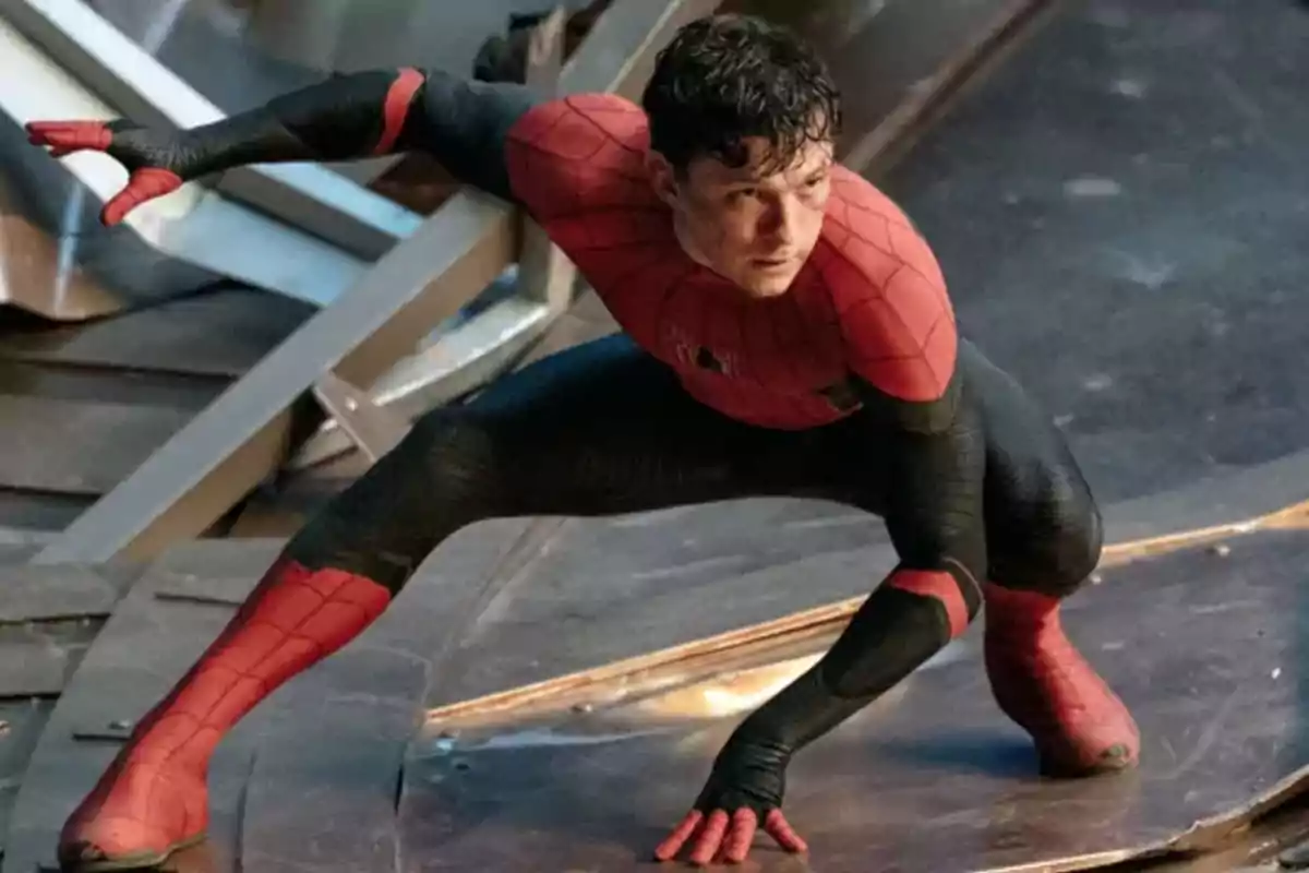 Hombre con traje de superhéroe rojo y negro en posición agachada sobre una superficie metálica Hombre con traje de superhéroe rojo y negro en posición agachada sobre una superficie metálica