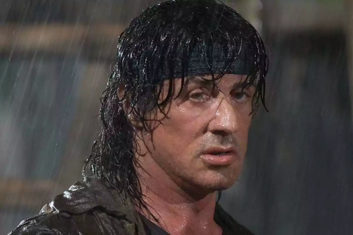 Hombre de cabello largo y mojado con cinta en la cabeza bajo la lluvia
