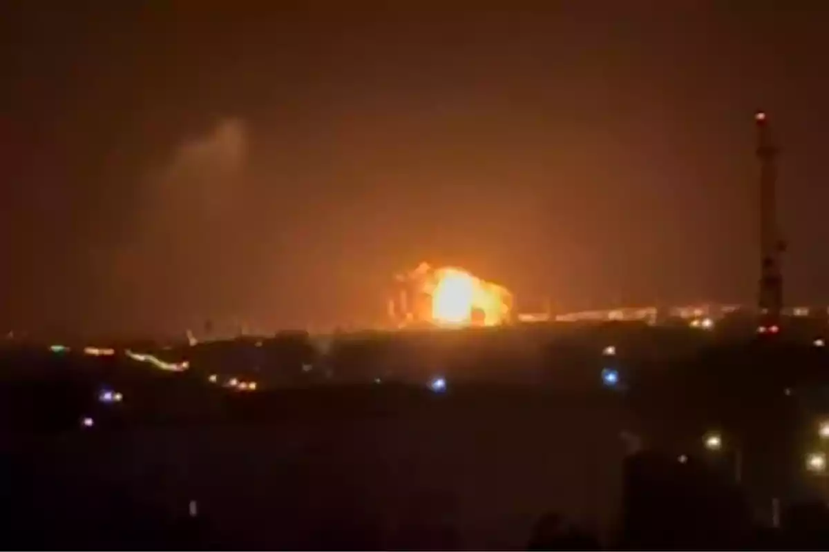 Explosión iluminando el cielo nocturno en una zona urbana