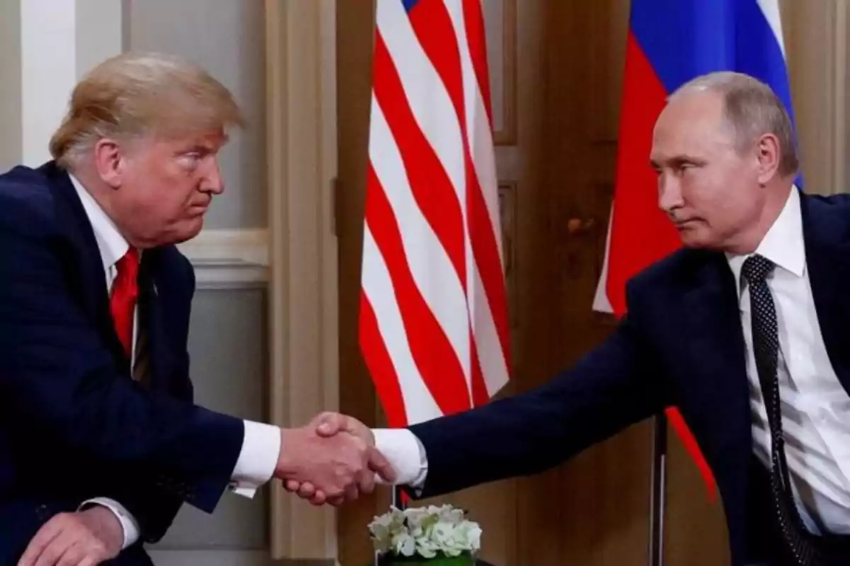 Dos hombres de traje se dan la mano frente a las banderas de Estados Unidos y Rusia