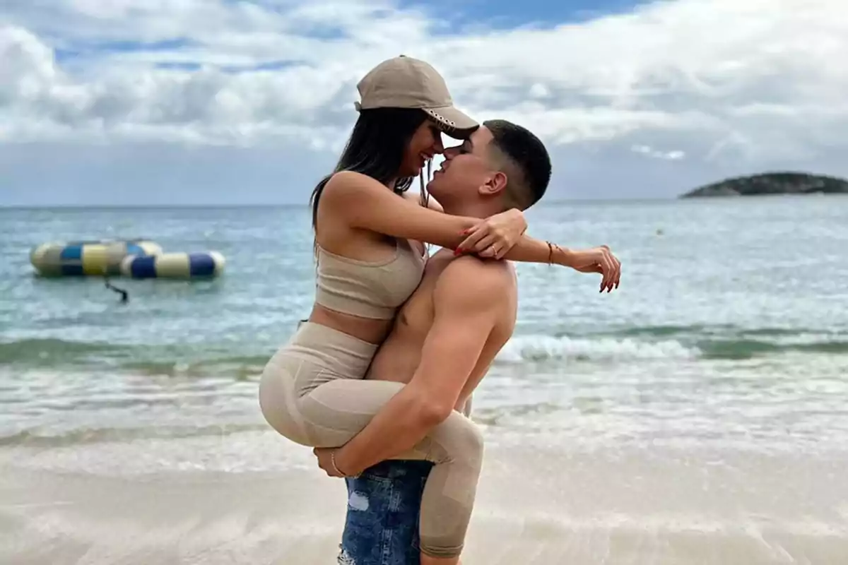 Couple hugging and smiling on the beach with the sea in the background Couple hugging and smiling on the beach with the sea in the background