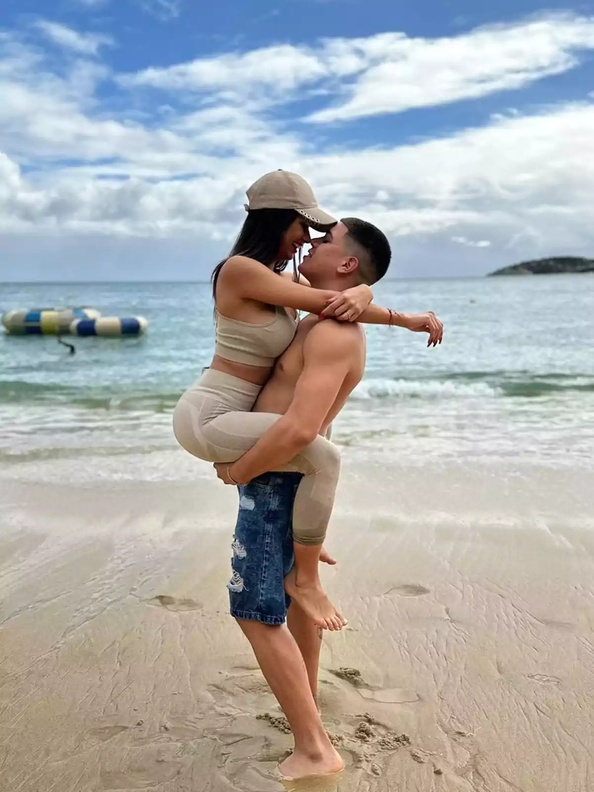 Couple hugging and kissing on the beach with the sea and cloudy sky in the background Couple hugging and kissing on the beach with the sea and cloudy sky in the background