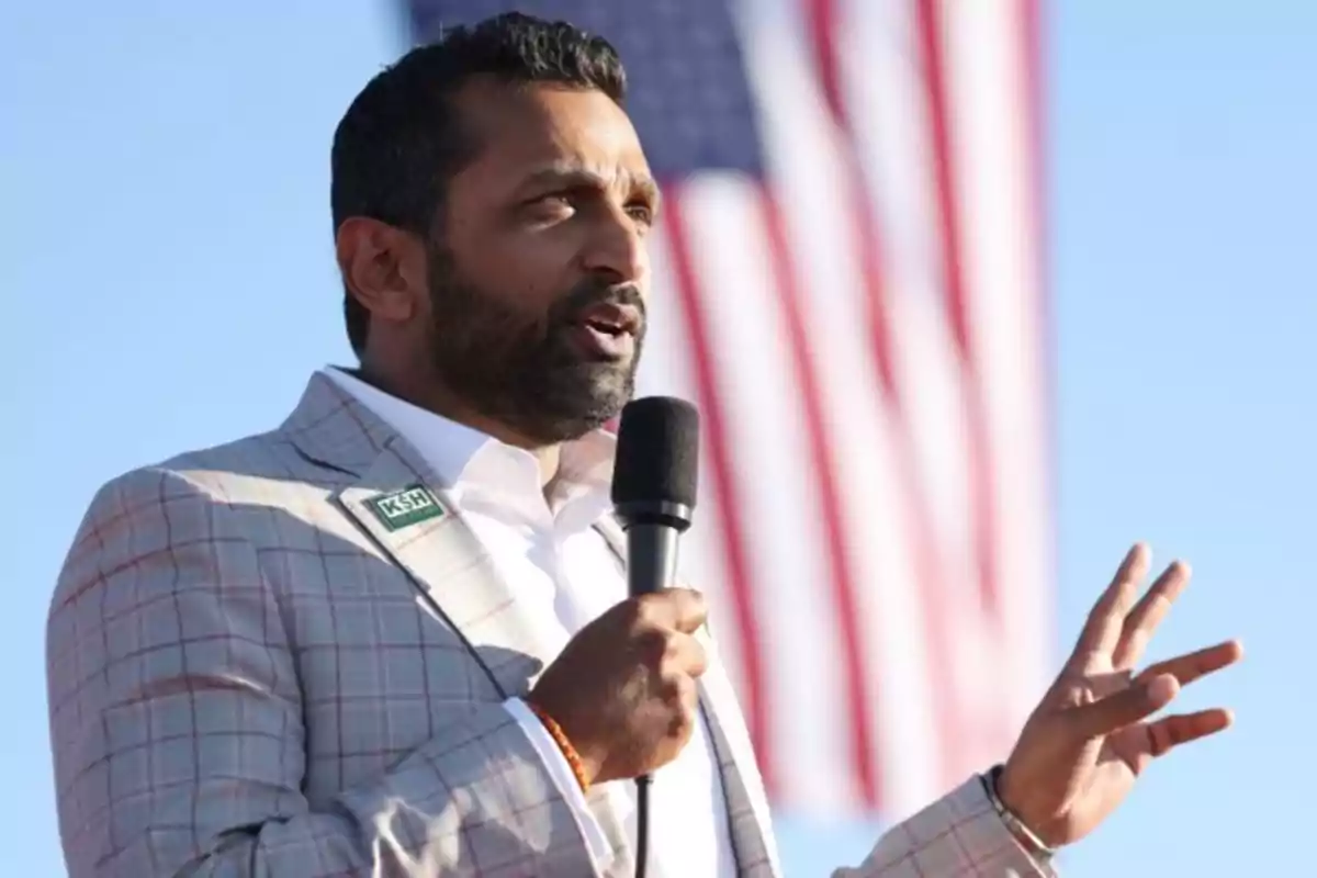 Hombre con barba hablando al micrófono con una bandera de Estados Unidos de fondo Hombre con barba hablando al micrófono con una bandera de Estados Unidos de fondo