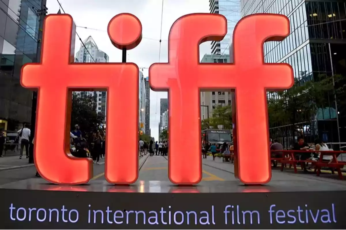 Letrero gigante iluminado de tiff en una calle urbana con edificios modernos y personas alrededor durante el Toronto International Film Festival