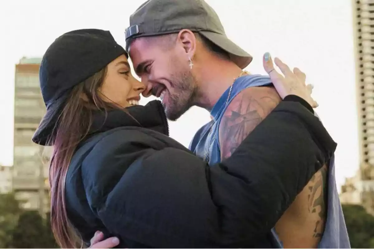 Pareja joven abrazándose y sonriendo mientras se miran de cerca en un entorno urbano Pareja joven abrazándose y sonriendo mientras se miran de cerca en un entorno urbano