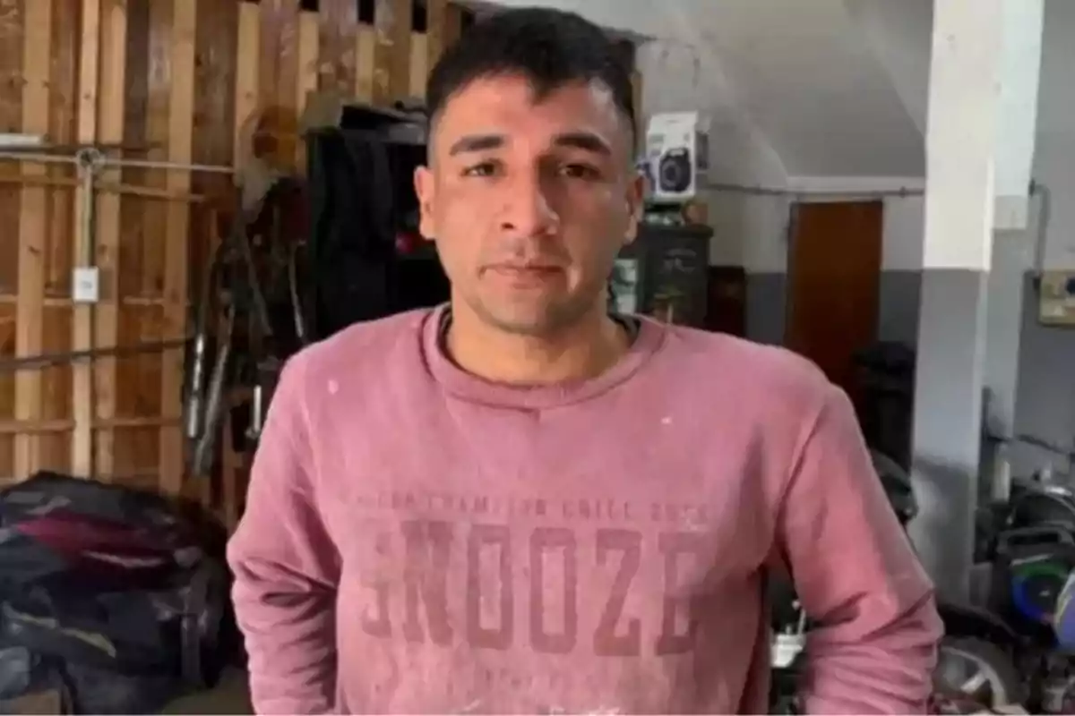 Short-haired man wearing a pink sweater standing in a workshop or garage Short-haired man wearing a pink sweater standing in a workshop or garage