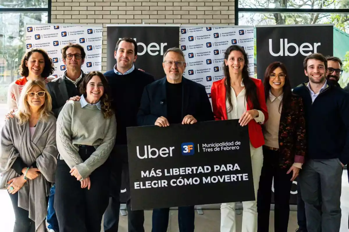 Grupo de personas sonrientes posando juntas en un evento de Uber y la Municipalidad de Tres de Febrero, sosteniendo un cartel que promueve la libertad de elegir cómo moverse