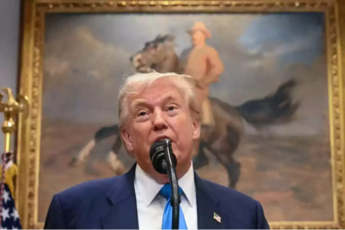 Blond-haired man speaking in front of a microphone with a painting of a horse rider in the background Blond-haired man speaking in front of a microphone with a painting of a horse rider in the background