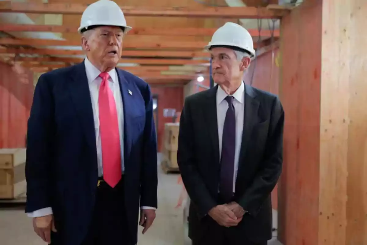 Dos hombres con casco de seguridad y traje conversan en el interior de una construcción. Dos hombres con casco de seguridad y traje conversan en el interior de una construcción.