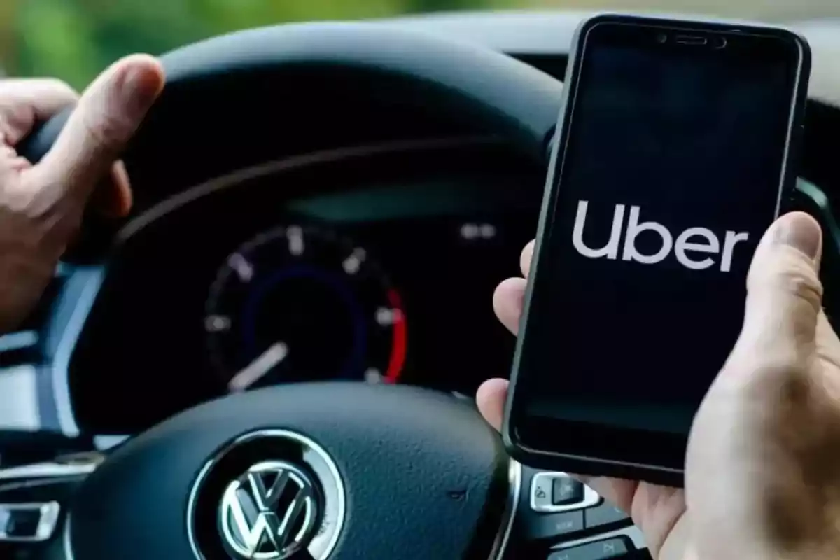 Persona sosteniendo un teléfono con la aplicación de Uber abierta mientras conduce un automóvil Volkswagen
