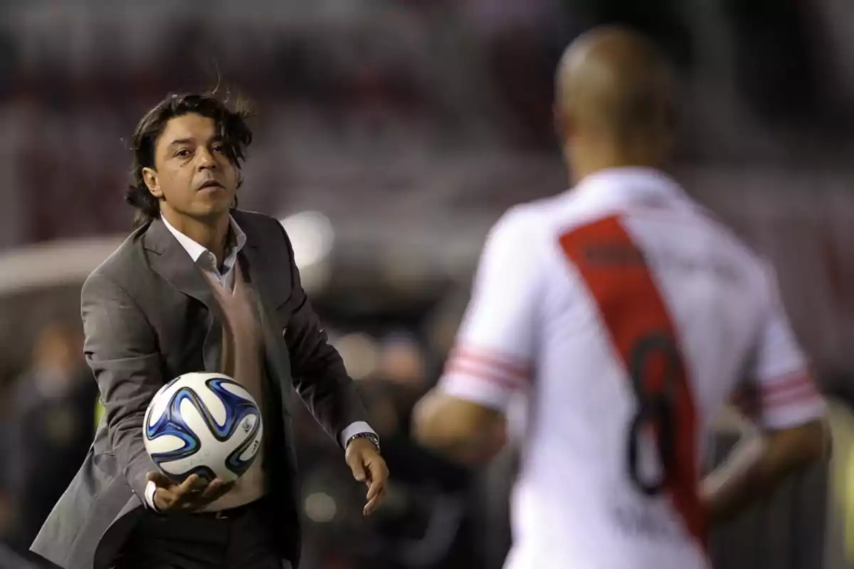 Soccer coach in a suit handing a ball to a player in a white uniform with a red stripe in a stadium Soccer coach in a suit handing a ball to a player in a white uniform with a red stripe in a stadium