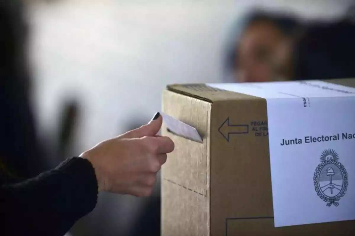 Persona depositando un sobre en una urna de votación durante una elección en Argentina Persona depositando un sobre en una urna de votación durante una elección en Argentina