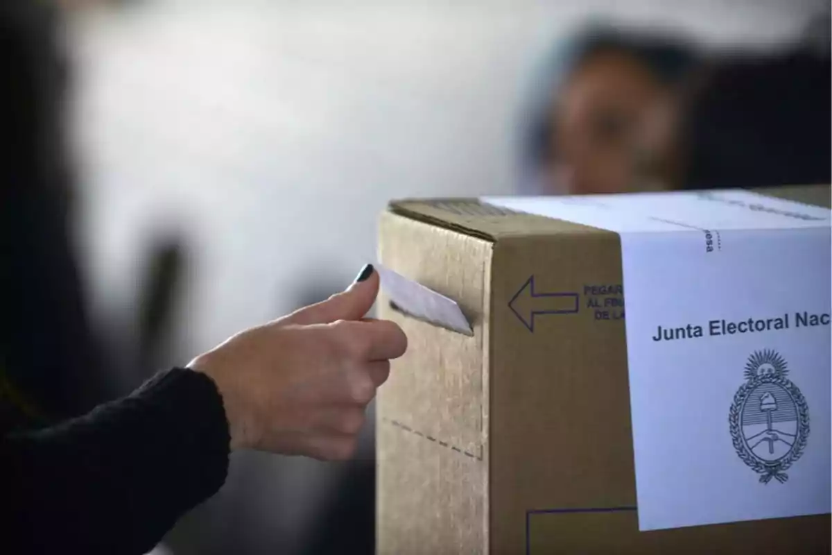Person inserting an envelope into an Argentine ballot box