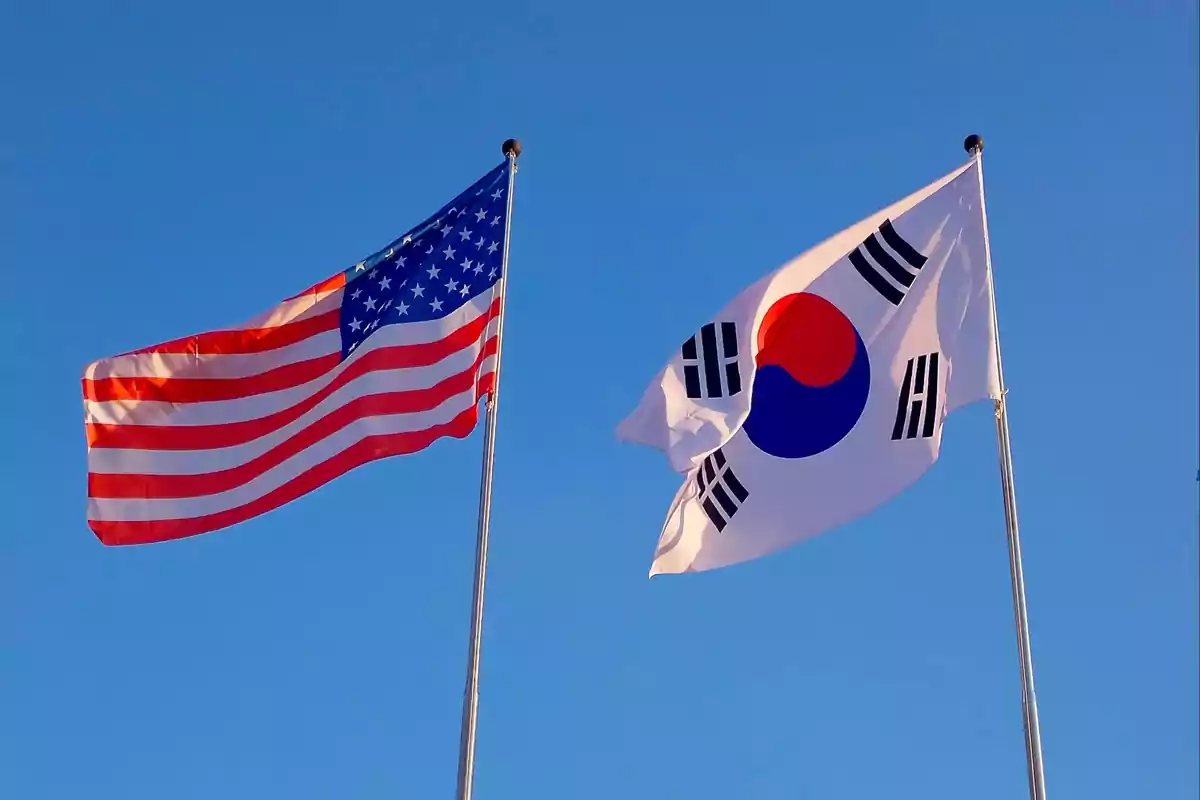 Flags of the United States and South Korea waving in the blue sky Flags of the United States and South Korea waving in the blue sky