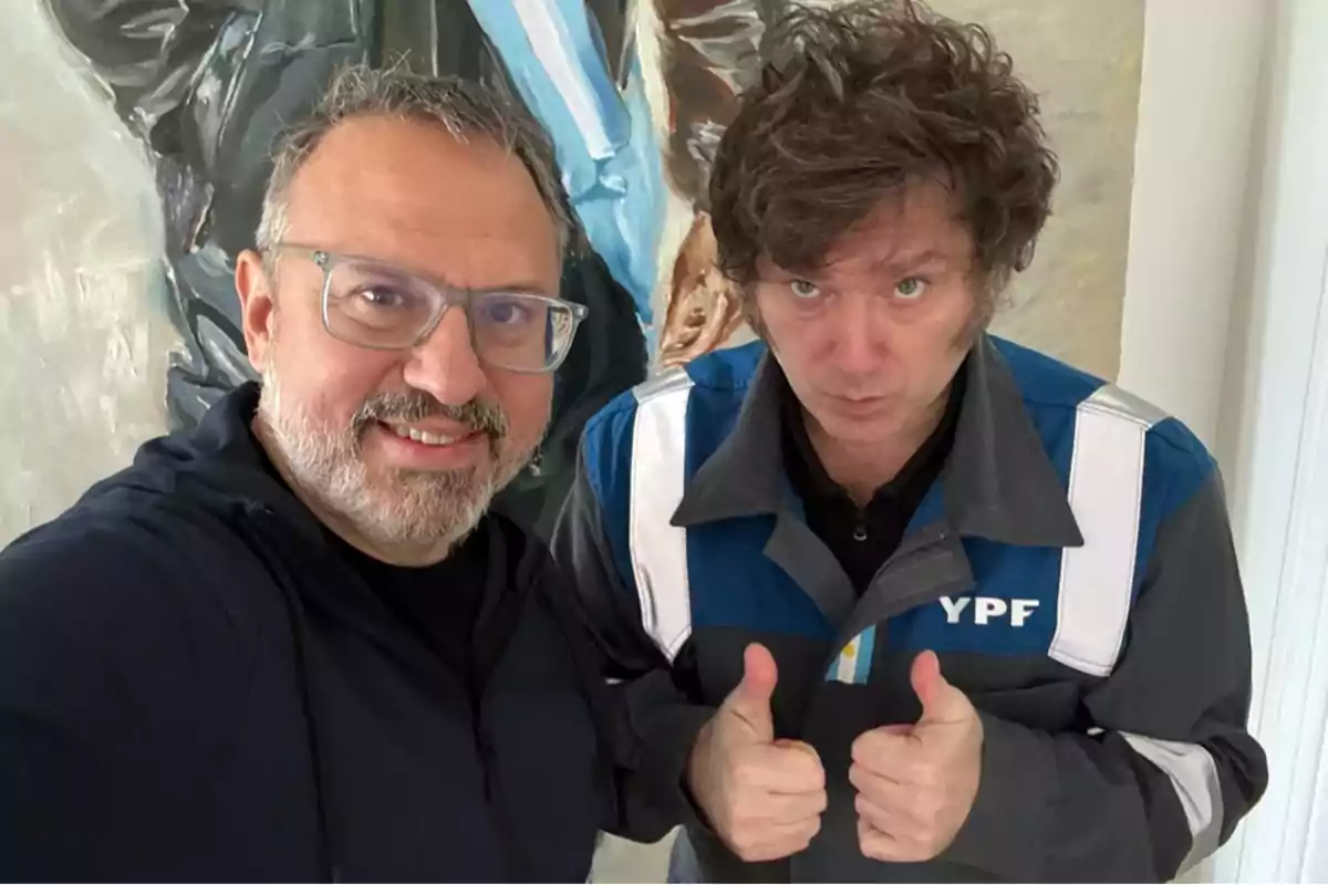 Two people pose for a selfie; one of them is smiling and the other is wearing a blue jacket with the letters YPF and giving a thumbs-up gesture. Two people pose for a selfie; one of them is smiling and the other is wearing a blue jacket with the letters YPF and giving a thumbs-up gesture.