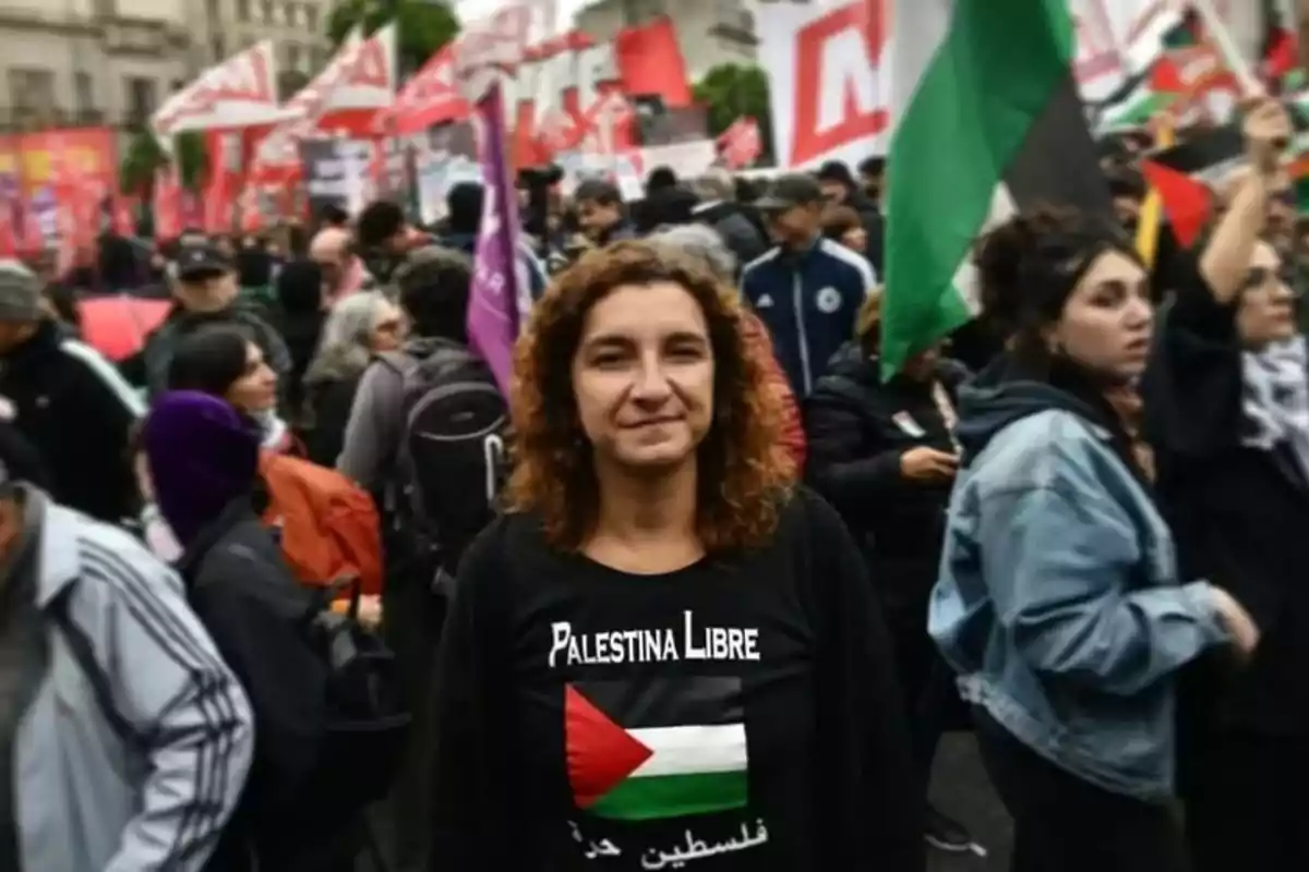 Mujer con camiseta de Palestina Libre en una manifestación rodeada de personas y banderas.