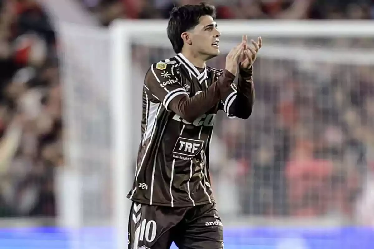 Futbolista con uniforme marrón aplaudiendo en el campo durante un partido Futbolista con uniforme marrón aplaudiendo en el campo durante un partido