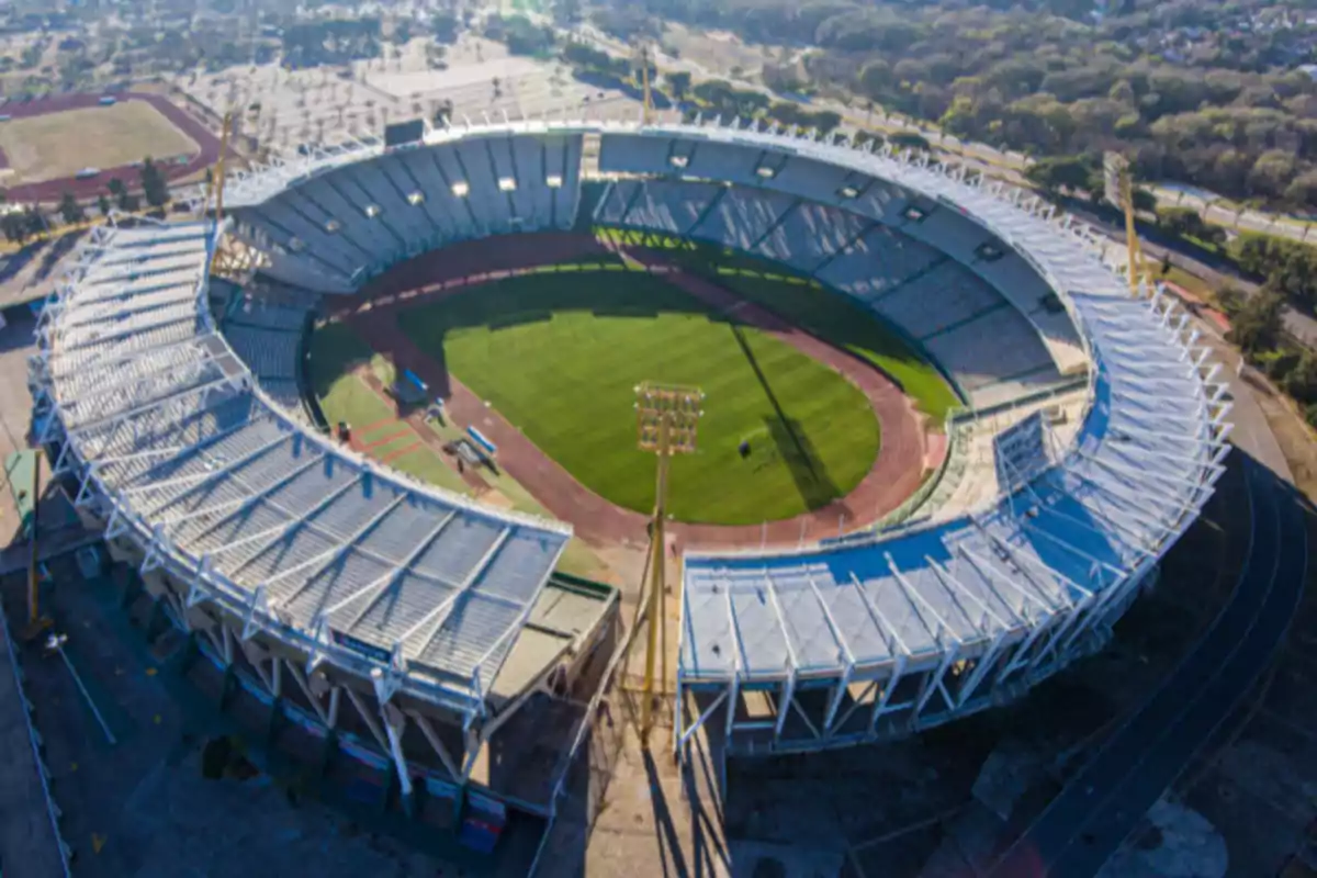 Aerial view of a large stadium with empty stands and a grass field surrounded by a running track