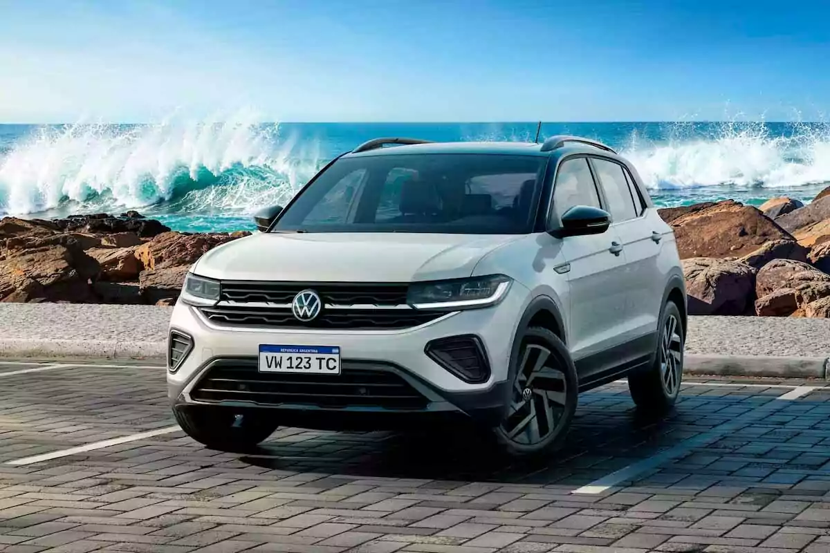 SUV Volkswagen blanca estacionada frente al mar con olas rompiendo en las rocas al fondo SUV Volkswagen blanca estacionada frente al mar con olas rompiendo en las rocas al fondo