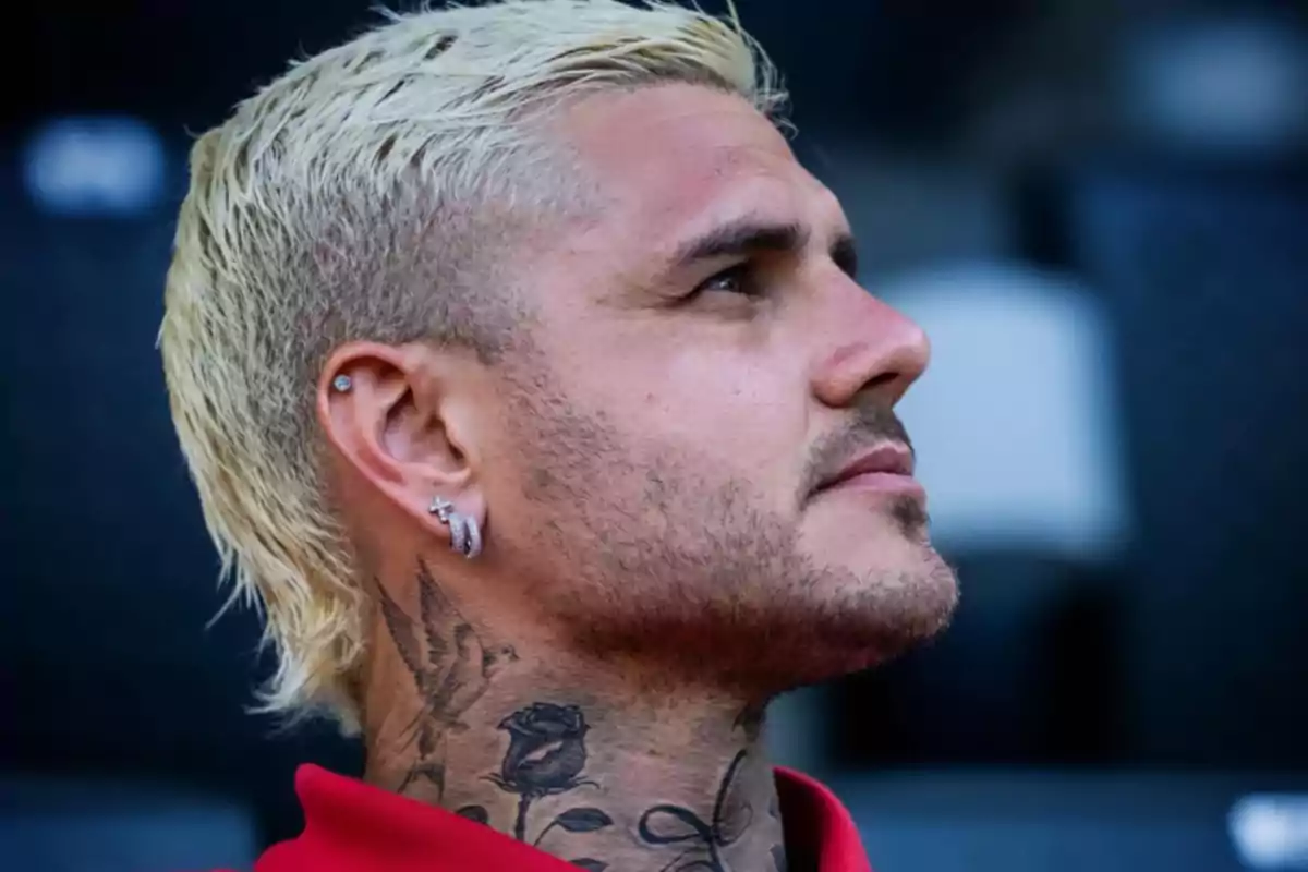 Man in profile with short blond hair, stubble, neck tattoos, earrings, and wearing a red garment Man in profile with short blond hair, stubble, neck tattoos, earrings, and wearing a red garment