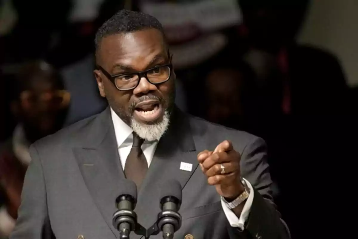 Man in a dark suit and glasses speaking in public while pointing with his finger in front of two microphones Man in a dark suit and glasses speaking in public while pointing with his finger in front of two microphones