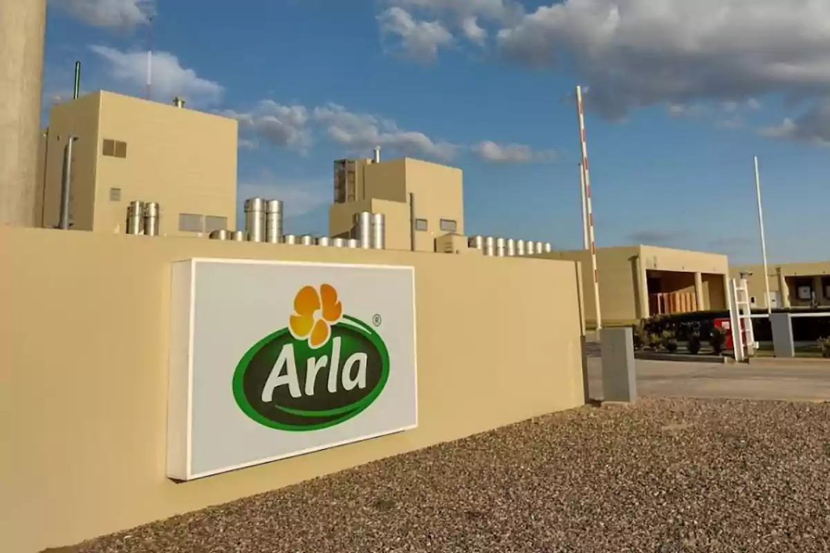 Fábrica de Arla con un letrero grande en la entrada y cielo parcialmente nublado Fábrica de Arla con un letrero grande en la entrada y cielo parcialmente nublado