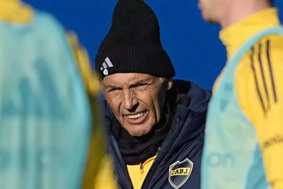 Boca Juniors coach wearing a black cap during an outdoor training session surrounded by players in yellow and light blue bibs Boca Juniors coach wearing a black cap during an outdoor training session surrounded by players in yellow and light blue bibs