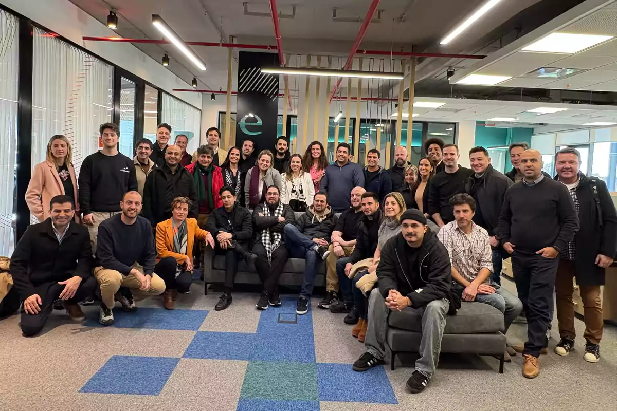 Grupo numeroso de personas posando juntas en una oficina moderna con decoración contemporánea y luz natural