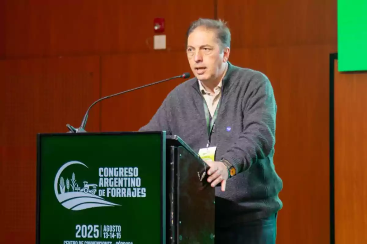 Hombre hablando en un podio durante el Congreso Argentino de Forrajes con un cartel anunciando el evento en Córdoba en agosto de 2025