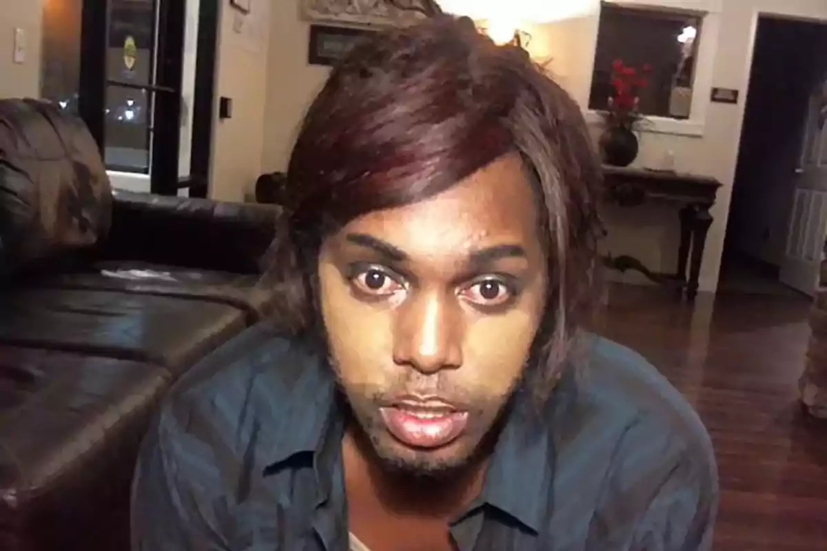 Persona con maquillaje mal difuminado en el rostro mirando hacia la cámara en una sala de estar