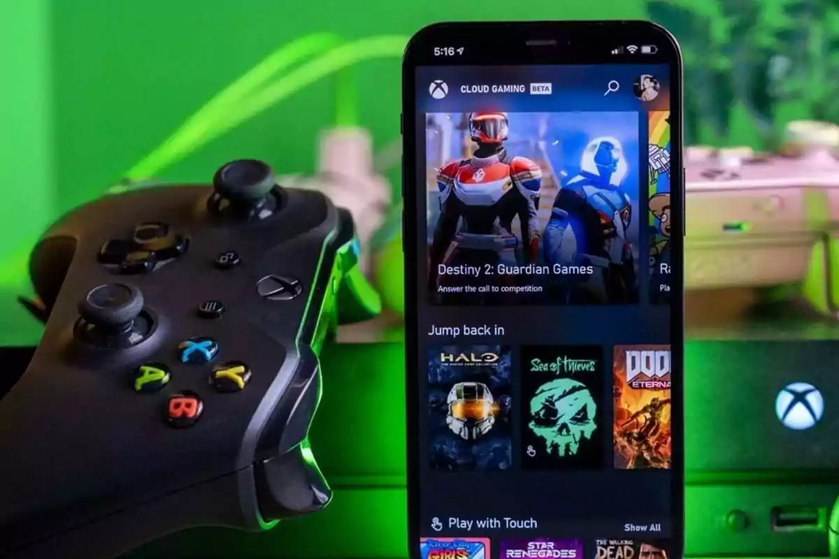 Control de Xbox junto a un teléfono móvil que muestra la aplicación de juegos en la nube de Xbox con varios títulos populares en pantalla y luces verdes de fondo Control de Xbox junto a un teléfono móvil que muestra la aplicación de juegos en la nube de Xbox con varios títulos populares en pantalla y luces verdes de fondo