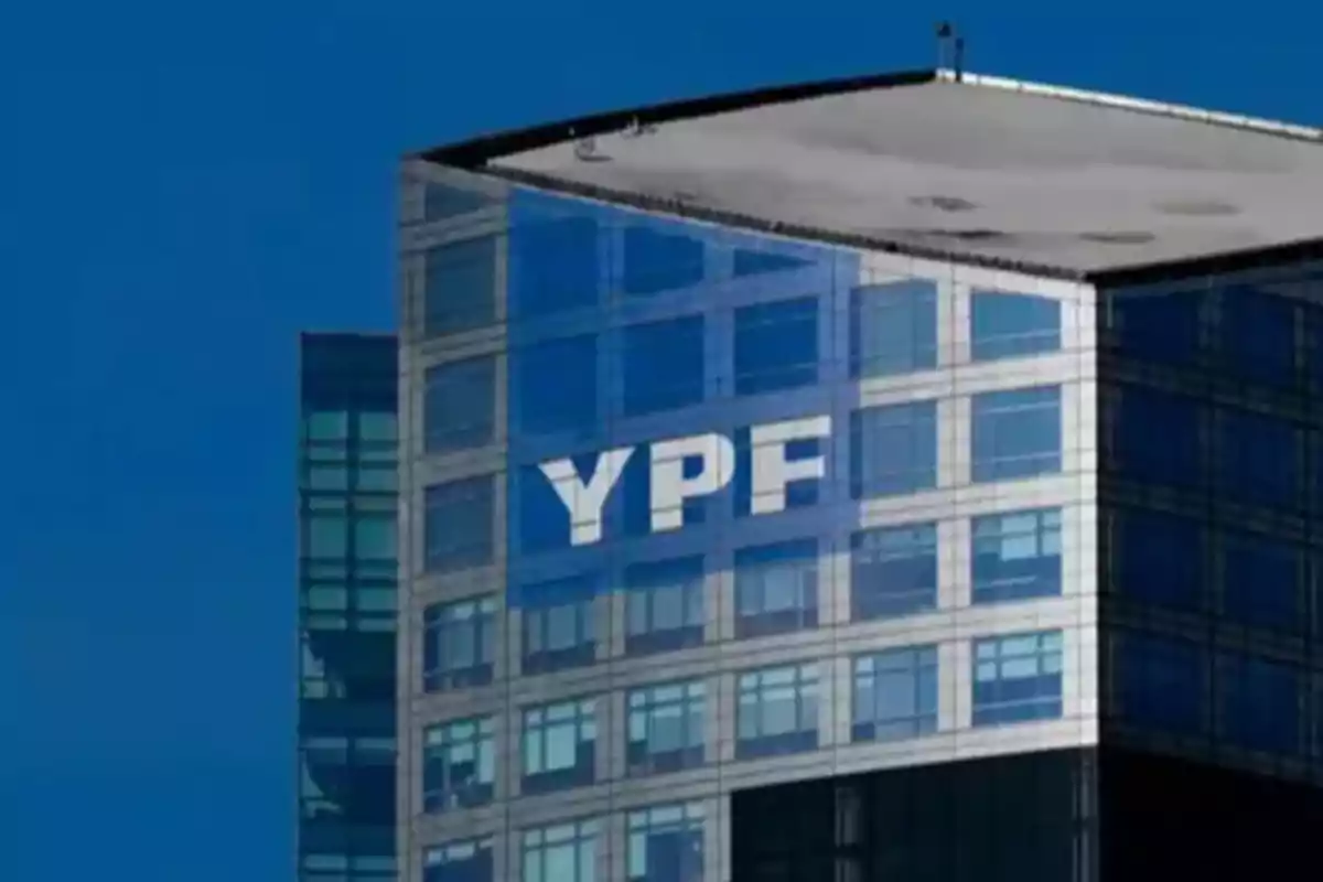 Modern glass building with the YPF logo at the top under a blue sky Modern glass building with the YPF logo at the top under a blue sky