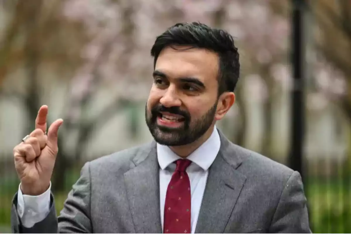 Bearded man in a gray suit and red tie gesturing with his hand while speaking outdoors Bearded man in a gray suit and red tie gesturing with his hand while speaking outdoors