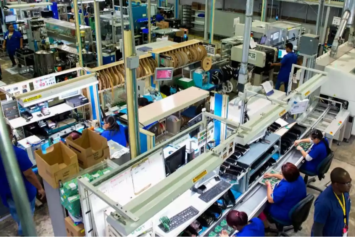 Personas trabajando en una línea de ensamblaje dentro de una fábrica de manufactura electrónica