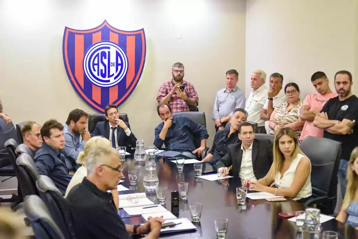Meeting of several people in a conference room with the San Lorenzo de Almagro crest on the wall Meeting of several people in a conference room with the San Lorenzo de Almagro crest on the wall