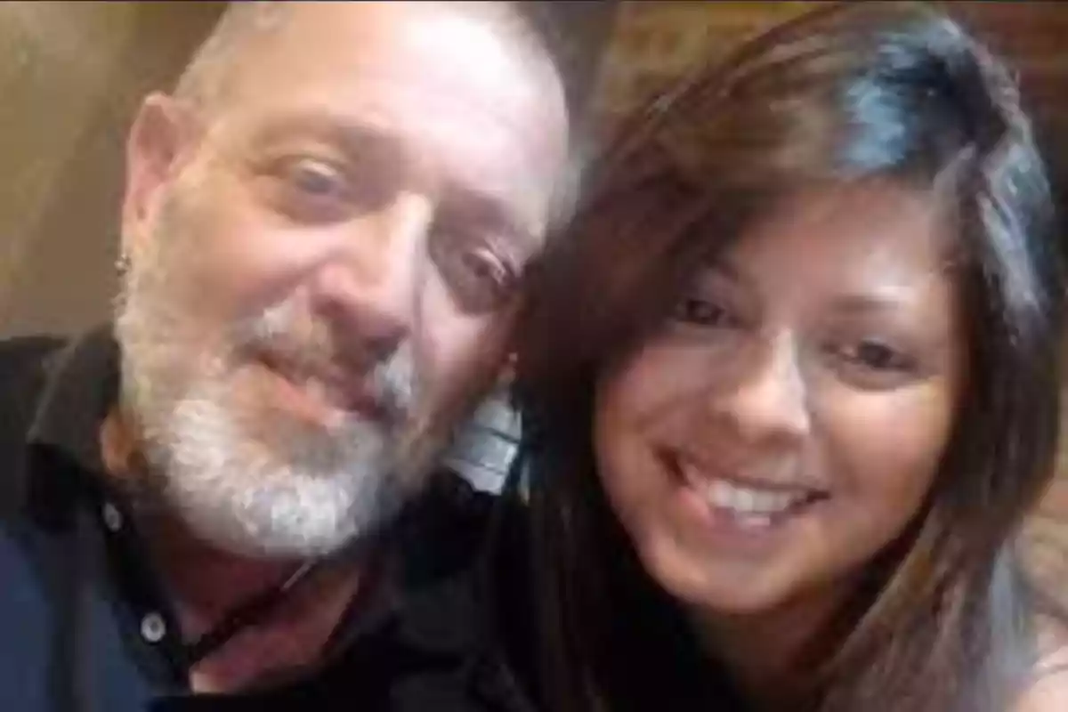A gray-bearded man and a woman with long dark hair smile together in a selfie.