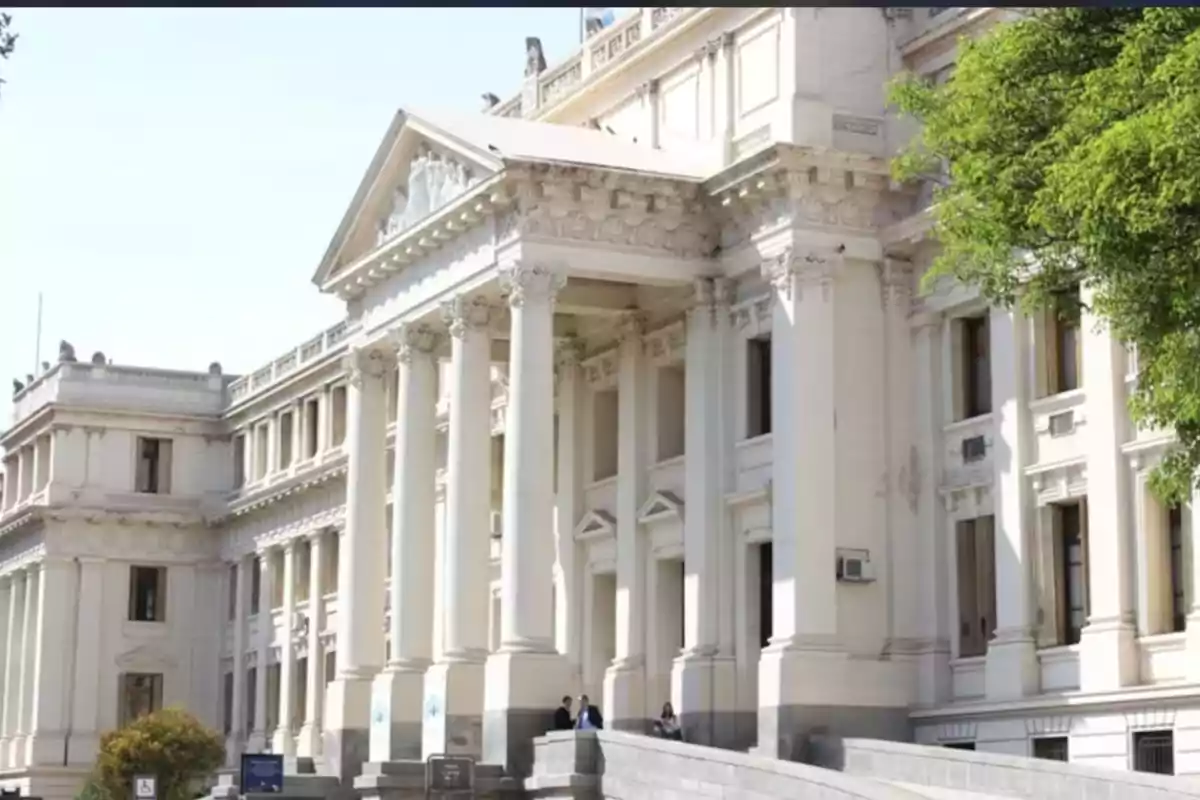 Fachada de un edificio antiguo de estilo neoclásico con columnas blancas y detalles ornamentales Fachada de un edificio antiguo de estilo neoclásico con columnas blancas y detalles ornamentales