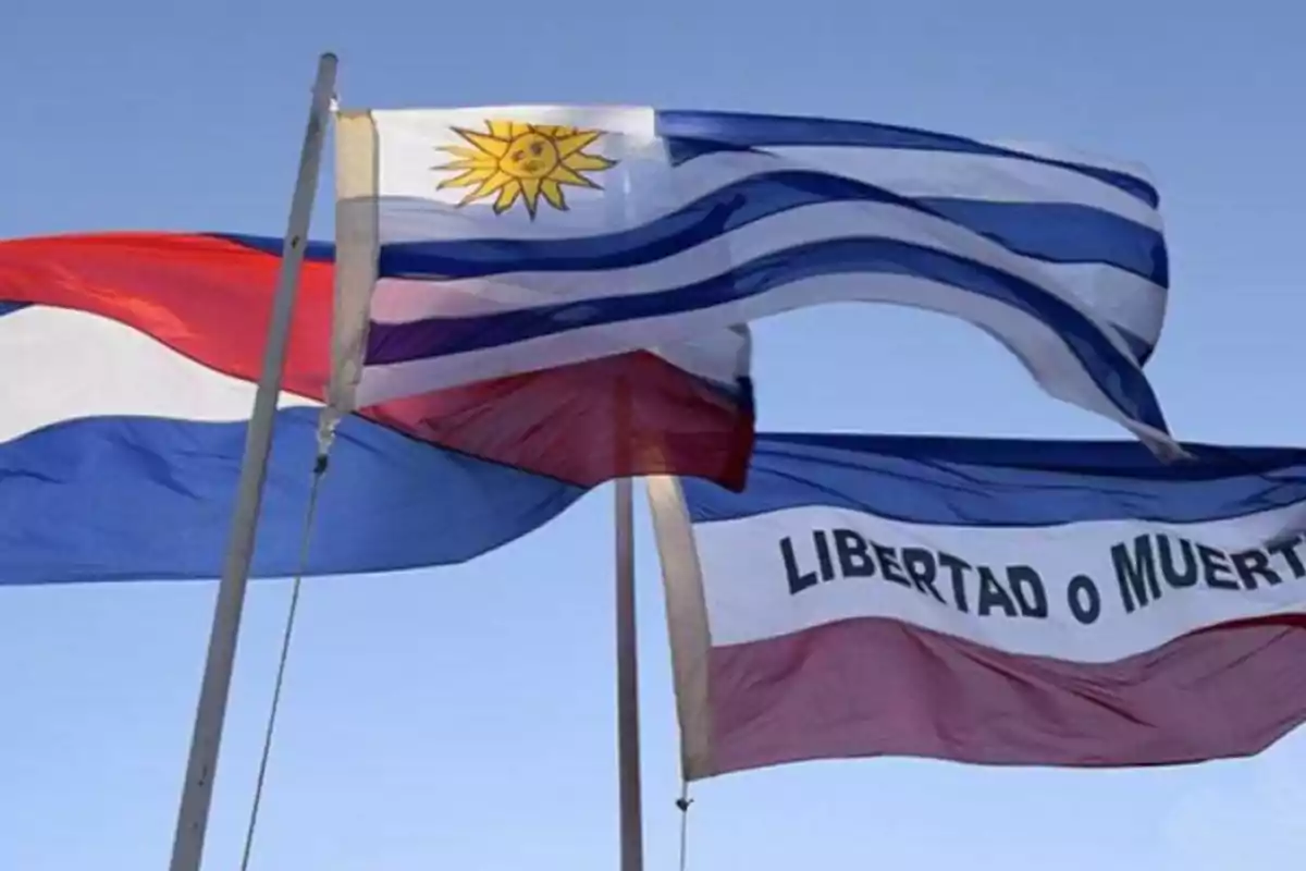 Tres banderas uruguayas ondeando al viento sobre un cielo despejado Tres banderas uruguayas ondeando al viento sobre un cielo despejado