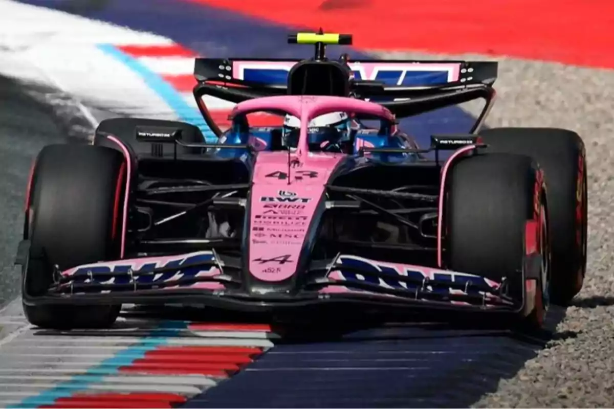 Pink and blue Formula 1 car driving on a racetrack